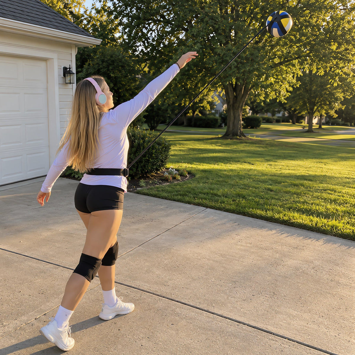 A player serving on her driveway with the TrainerOne volleyball serve trainer
